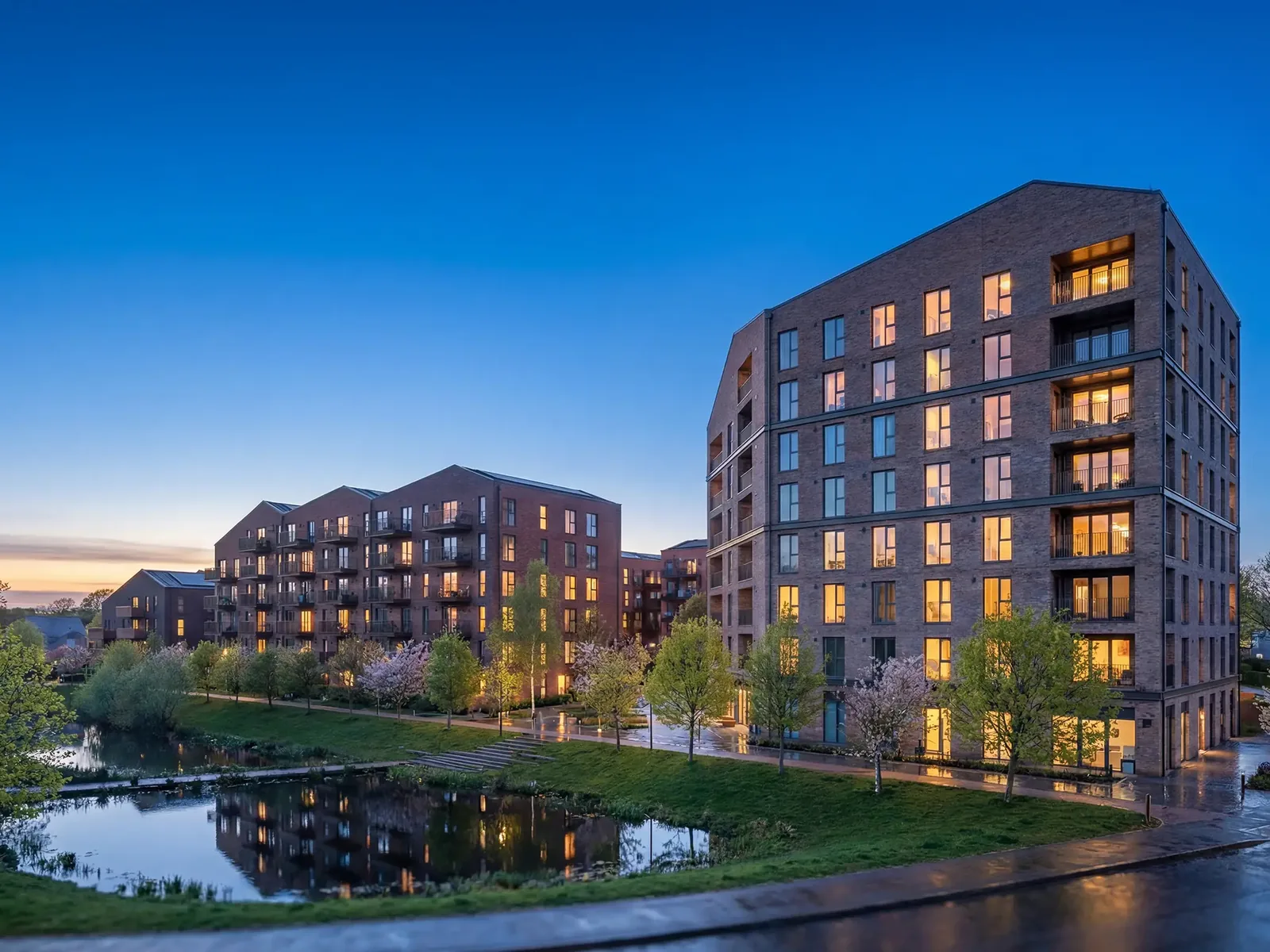 Fotorealistische Architekturvisualisierung eines Wohnquartiers aus Backstein in der Abenddämmerung mit Wasserspiegelung – build-av.de